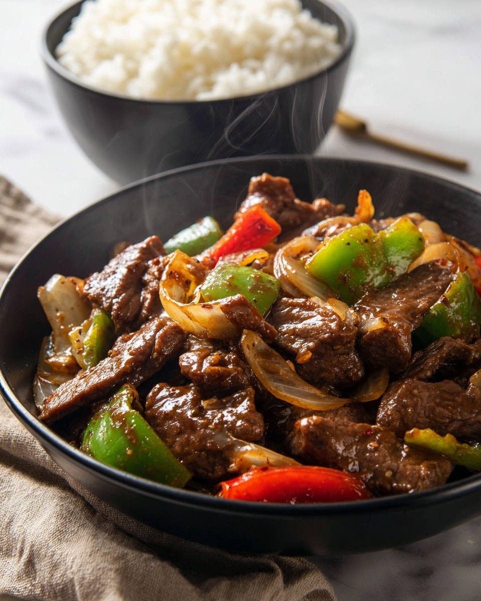 This image shows a black bowl filled with a stir-fry dish consisting of several layers. The bottom layer has pieces of cooked beef in rich brown sauce with a glossy texture. Mixed in are chunky pieces of green bell pepper and red bell pepper, adding bright green and red colors. There are also slices of cooked onions, pale yellow and slightly translucent, spread throughout the dish. In the background, there is a black bowl filled with white steamed rice. The whole setup is placed on a white marbled surface with a neutral cloth nearby. Steam rises gently from the hot stir-fry. photo taken with an iphone --ar 4:5 --v 7