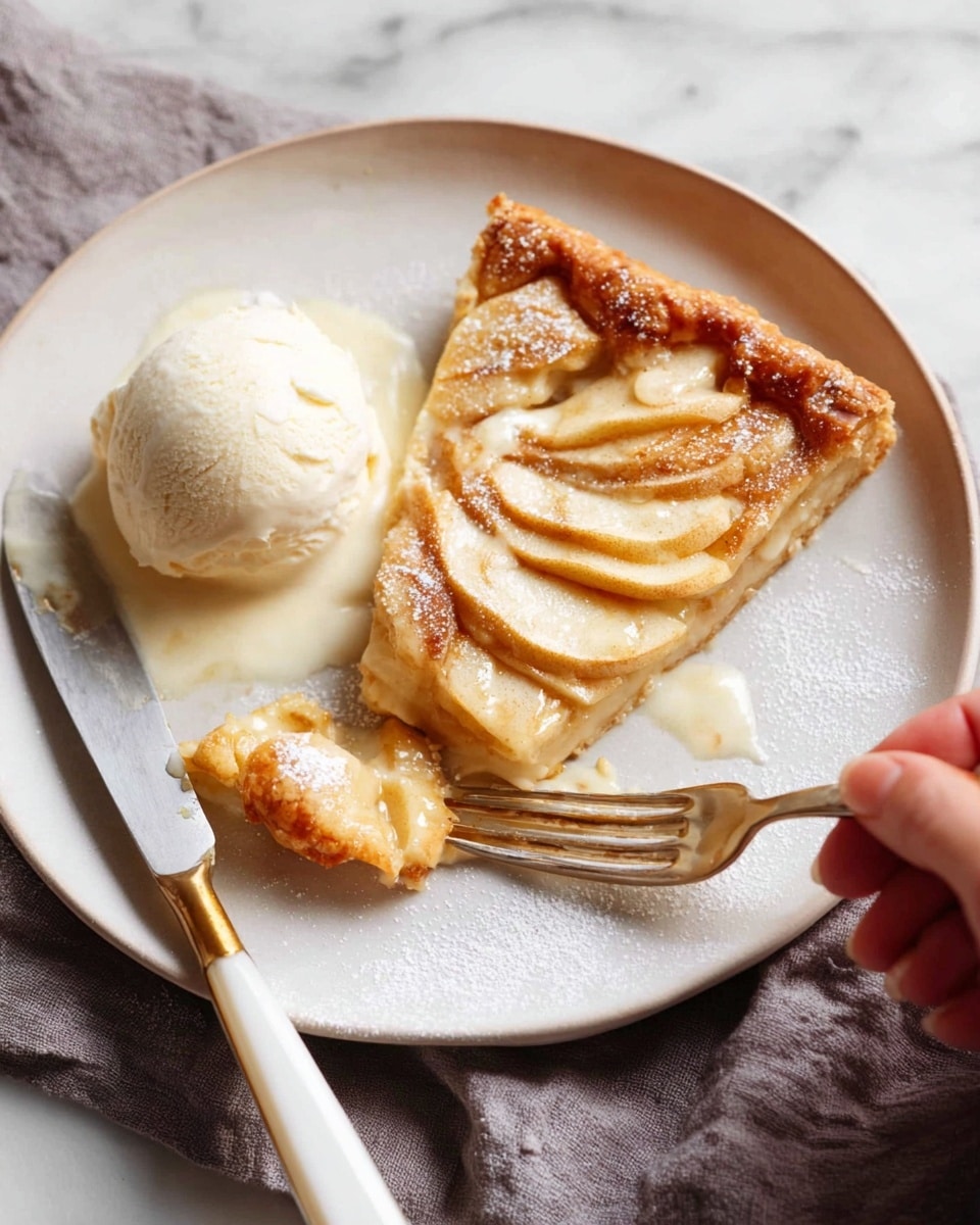 A white plate holds a slice of apple tart with a flaky golden brown crust. On top of the crust are thin, soft, light yellow apple slices arranged in a layered pattern. A scoop of vanilla ice cream sits beside the tart, partially melting and blending with the tart juices. A woman's hand holding a fork cuts a piece from the tart, while a knife with a white and gold handle rests on the plate. The plate is set on a soft grey cloth, all against a white marbled surface. photo taken with an iphone --ar 4:5 --v 7