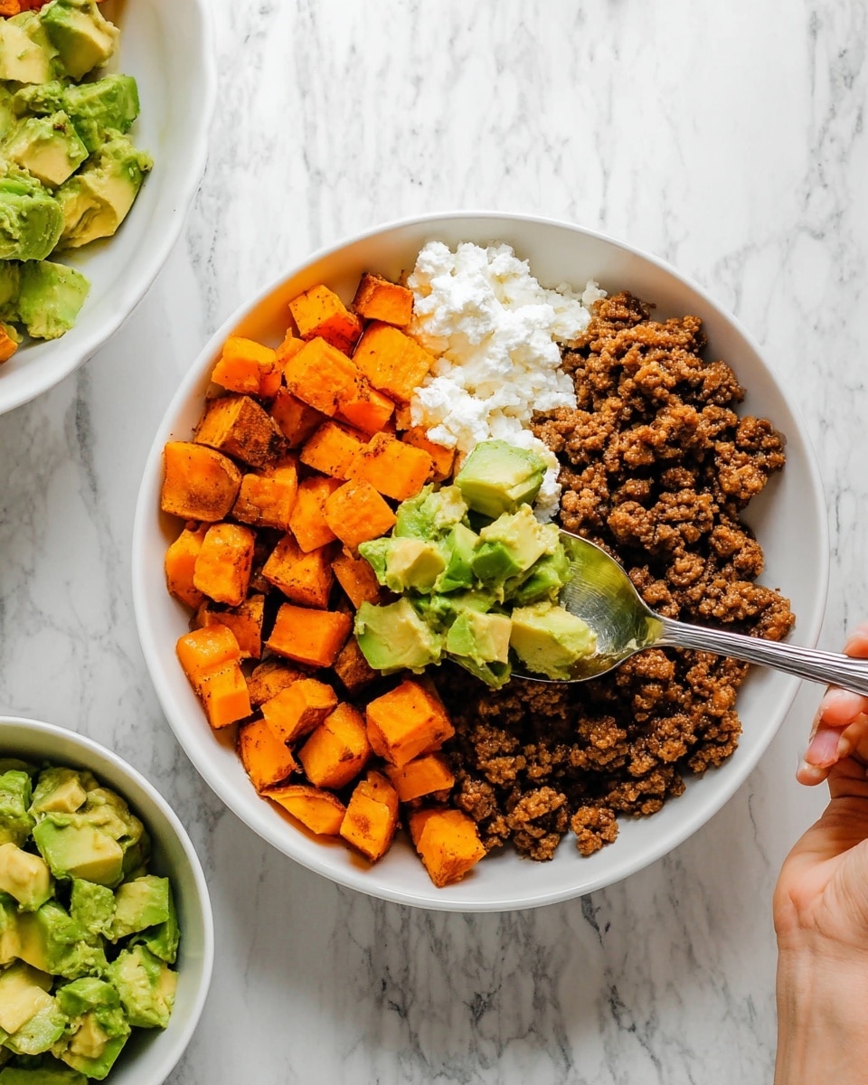 The image shows a white bowl with three layers of food neatly arranged side by side: bright orange roasted sweet potato cubes on the top right, brown cooked ground meat on the bottom right, and white cottage cheese on the left. A woman's hand holding a silver spoon with green avocado cubes is positioned over the bowl, about to add the avocado. The bowl is placed on a white marbled surface, and part of another white bowl with similar contents is visible to the right. In the lower left corner, there is a smaller white bowl filled with more green avocado cubes. Photo taken with an iphone --ar 4:5 --v 7