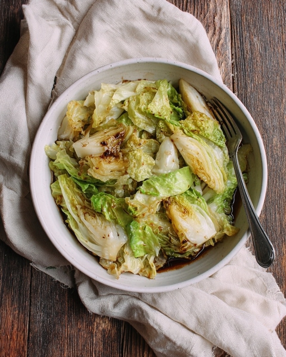 In a beige bowl sits a layered pile of cooked lettuce with burnt edges, showing shades of light green, yellow, and caramel brown. The lettuce leaves are soft with slight crisp spots and are soaking in a dark brown sauce that pools at the bottom of the bowl. The bowl is placed on a white cloth over a rough wooden surface, but the background is changed to a white marbled texture. Photo taken with an iphone --ar 4:5 --v 7