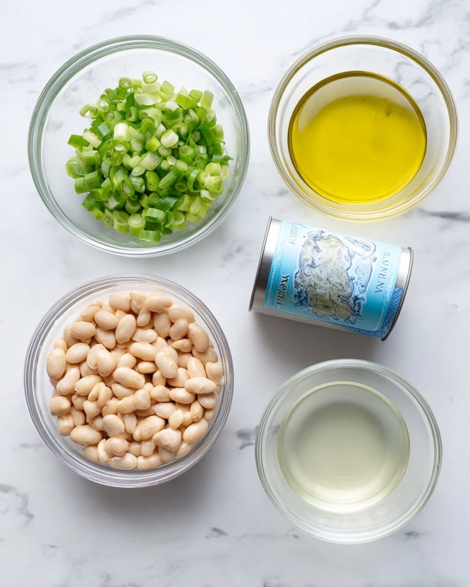 The image shows four small clear glass bowls and a small tin can of tuna placed on a white marbled surface. The largest bowl is filled with light beige beans, sitting at the bottom left. Above it, there is a bowl filled with chopped green onions that show their white and green parts. To the right of the green onions bowl, there is another bowl holding a yellow liquid that looks like oil. Below the tin can of tuna, there is a fourth bowl containing a clear, light-colored liquid. The tin can is light blue and silver, placed in the center-right area among the bowls. photo taken with an iphone --ar 4:5 --v 7