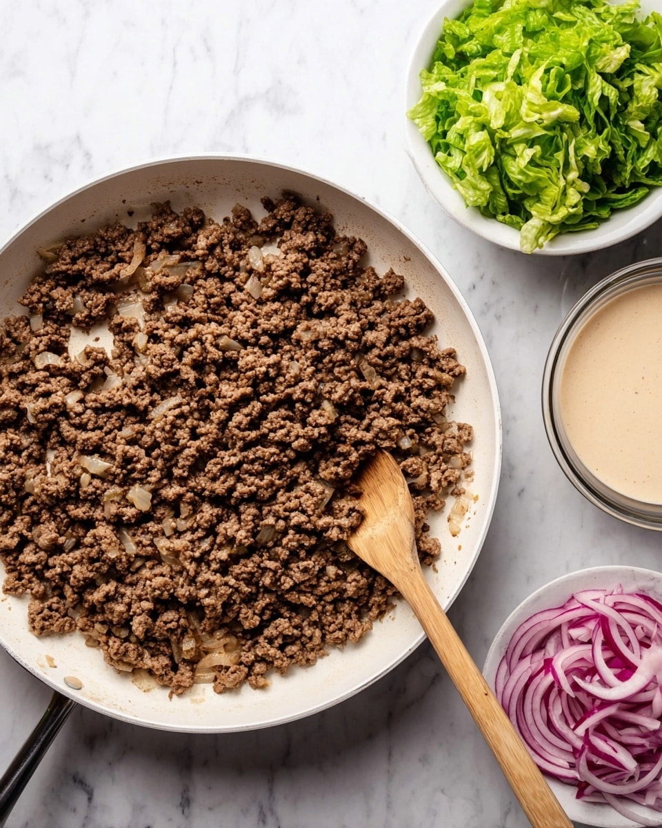 The image shows a white frying pan filled with evenly browned cooked ground meat mixed with small pieces of sautéed onions, giving it a crumbly texture with dark and light brown shades. A wooden spoon rests inside the pan on the right side, partially covered by the meat. Around the pan, there is a small clear bowl of creamy beige sauce on the lower left, a white bowl full of fresh bright green shredded lettuce at the top right, and another white bowl containing thinly sliced red onions below the lettuce bowl. The whole scene is set on a white marbled surface. photo taken with an iphone --ar 4:5 --v 7