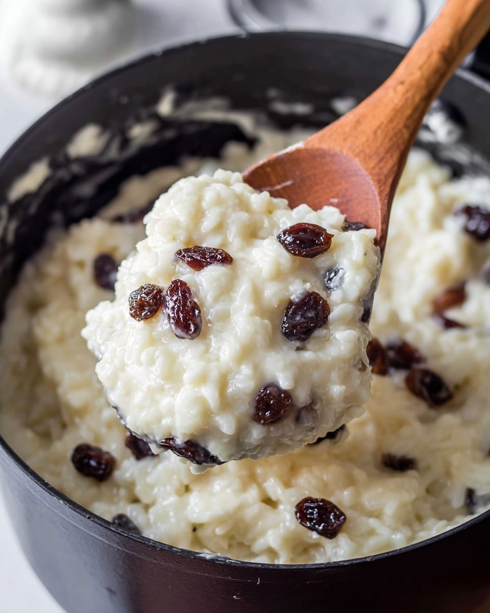 A close-up of two white bowls filled with creamy rice pudding that has a thick texture, white color, and is mixed with small dark raisins. The top of the pudding in each bowl is sprinkled evenly with a layer of brown cinnamon powder. Behind the bowls, there is a large dark pot filled with more of the same rice pudding, showing the creamy white mixture with raisins inside. The scene is set on a white marbled surface, and near the pot, there is a black and white striped cloth visible. In the bottom left corner, two cinnamon sticks lie on the white marbled surface, and in the bottom right, part of a silver spoon is visible. photo taken with an iphone --ar 4:5 --v 7