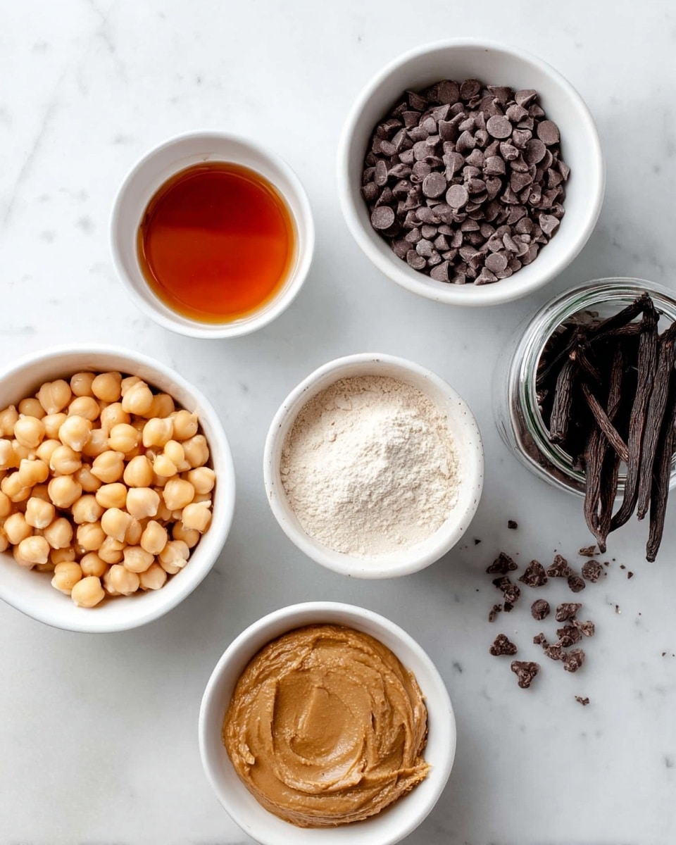 The image shows six containers placed on a white marbled surface. Starting from top left, there is a small white bowl filled with amber-colored syrup, next to it on the right is a white bowl filled to the top with dark chocolate chips. Below the syrup bowl is a smaller white bowl containing light beige flour with a small scoop inside. To the right of this flour bowl is a small white bowl filled with creamy brown almond butter that has a slightly thick texture. At the bottom left is a white bowl filled with light tan chickpeas, and to the right of the chickpeas is a glass jar filled with dark brown vanilla beans. A few chocolate chips are scattered near the top right bowl. Photo taken with an iphone --ar 4:5 --v 7