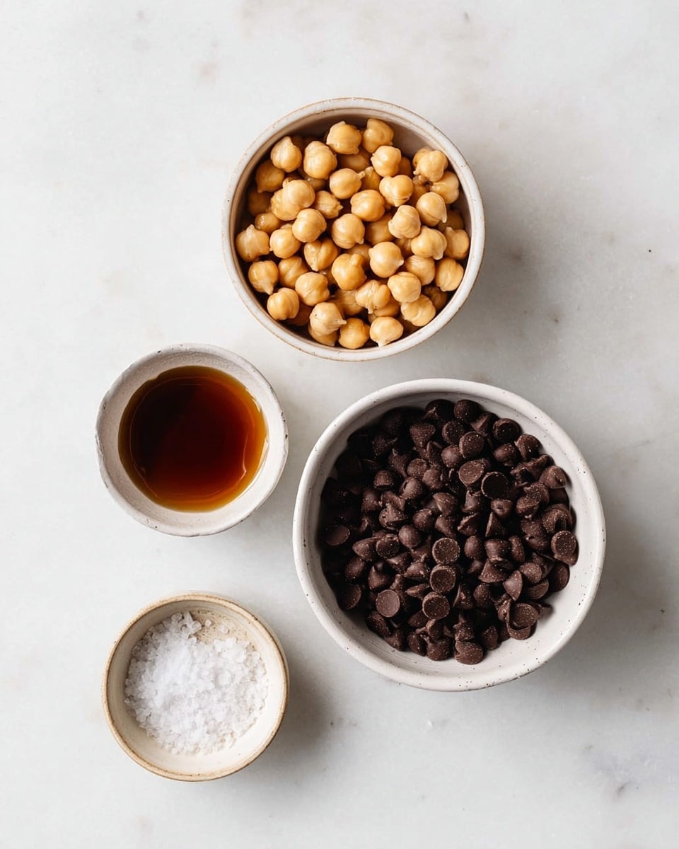 The image shows four small white bowls on a white marbled surface. The top right bowl is filled with light golden hazelnuts, round and smooth. Below it, there is a bowl packed with small, dark brown chocolate chips, shiny and slightly rounded on top. To the left of the chocolate chips, a small bowl contains a dark amber liquid resembling a syrup. At the bottom of the image, a tiny bowl holds a small pile of coarse white salt crystals. The bowls are arranged with a clean, simple look and the lighting is soft and natural, showing clear textures of the ingredients. photo taken with an iphone --ar 4:5 --v 7