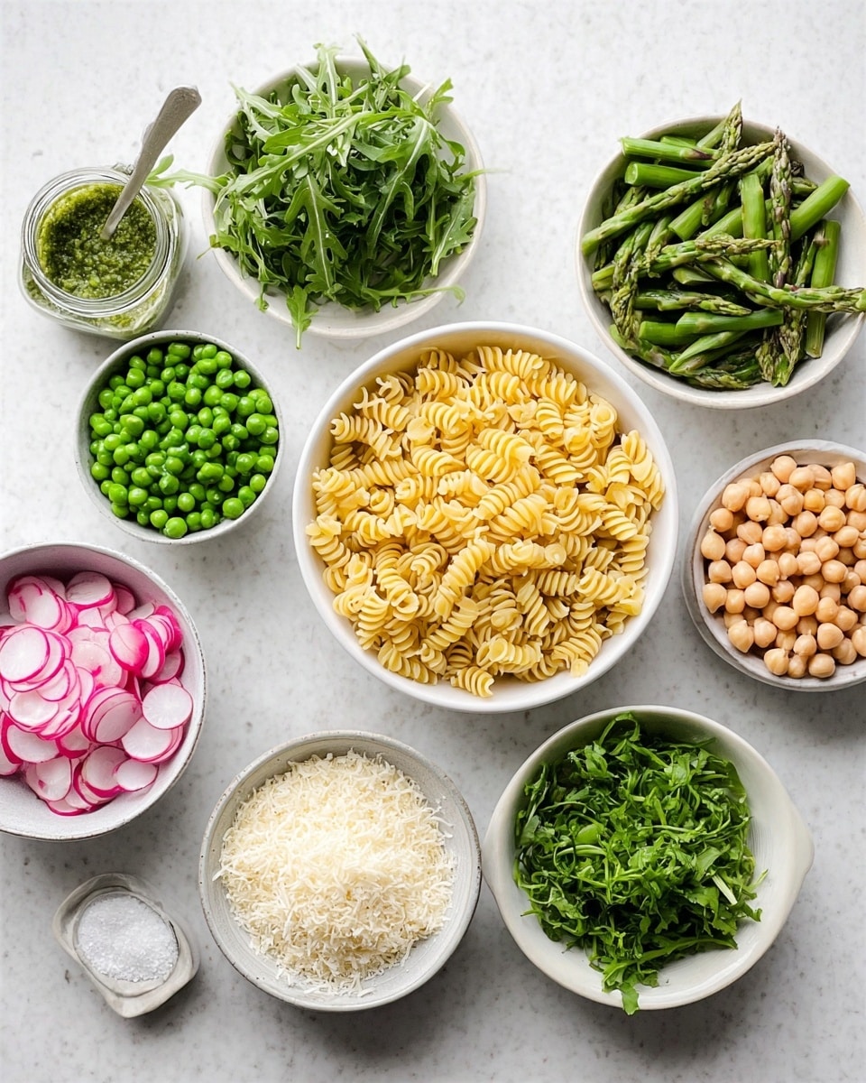 The image shows eight white bowls arranged on a white marbled surface, each filled with different ingredients. At the center is a bowl of uncooked spiral pasta, light yellow in color. Surrounding it are bowls with bright green peas, chopped asparagus pieces, chopped green onions, and fresh arugula leaves mixing light and dark greens. There’s a bowl of sliced thin pink and white radishes, a bowl of light beige chickpeas, and a bowl of grated white cheese with a slightly fluffy texture. Beside them is a small white marble bowl containing coarse salt and a jar of green sauce with a spoon. Photo taken with an iphone --ar 4:5 --v 7