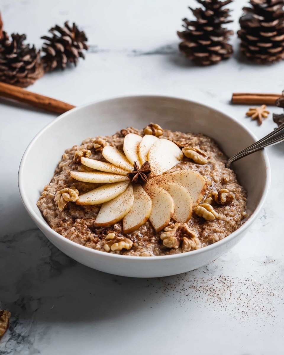 A white bowl on a white marbled surface holds a warm, brown oatmeal base with a soft and slightly chunky texture. On top, thin slices of pale cream apple are arranged in a fan shape at the center, sprinkled lightly with cinnamon powder. Scattered around and on the apple slices are whole walnut pieces, adding a rough and crunchy contrast. A silver spoon rests inside the bowl on the right side. Cinnamon sticks and pine cones are seen out of focus in the background. Photo taken with an iphone --ar 4:5 --v 7