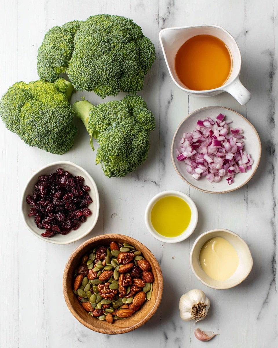 The image shows fresh broccoli with two big green florets laying flat on a white marbled surface. Below the broccoli, there are six bowls of ingredients arranged in a loose circle, starting with a wooden bowl filled with mixed roasted nuts and seeds featuring brown almonds and green pumpkin seeds in the bottom left. Above that, a small white bowl holds dark red dried cranberries, and next to it is another white bowl with finely chopped red onions showing purple and white pieces. To the right, three small cups hold liquids and sauces: a small glass cup of golden yellow olive oil, a white pitcher with an amber-colored dressing, a white bowl with light beige creamy mayonnaise, and a tiny bowl with a darker glossy sauce at the bottom center. A small piece of garlic lies near the top right, adding a natural touch. Photo taken with an iphone --ar 4:5 --v 7