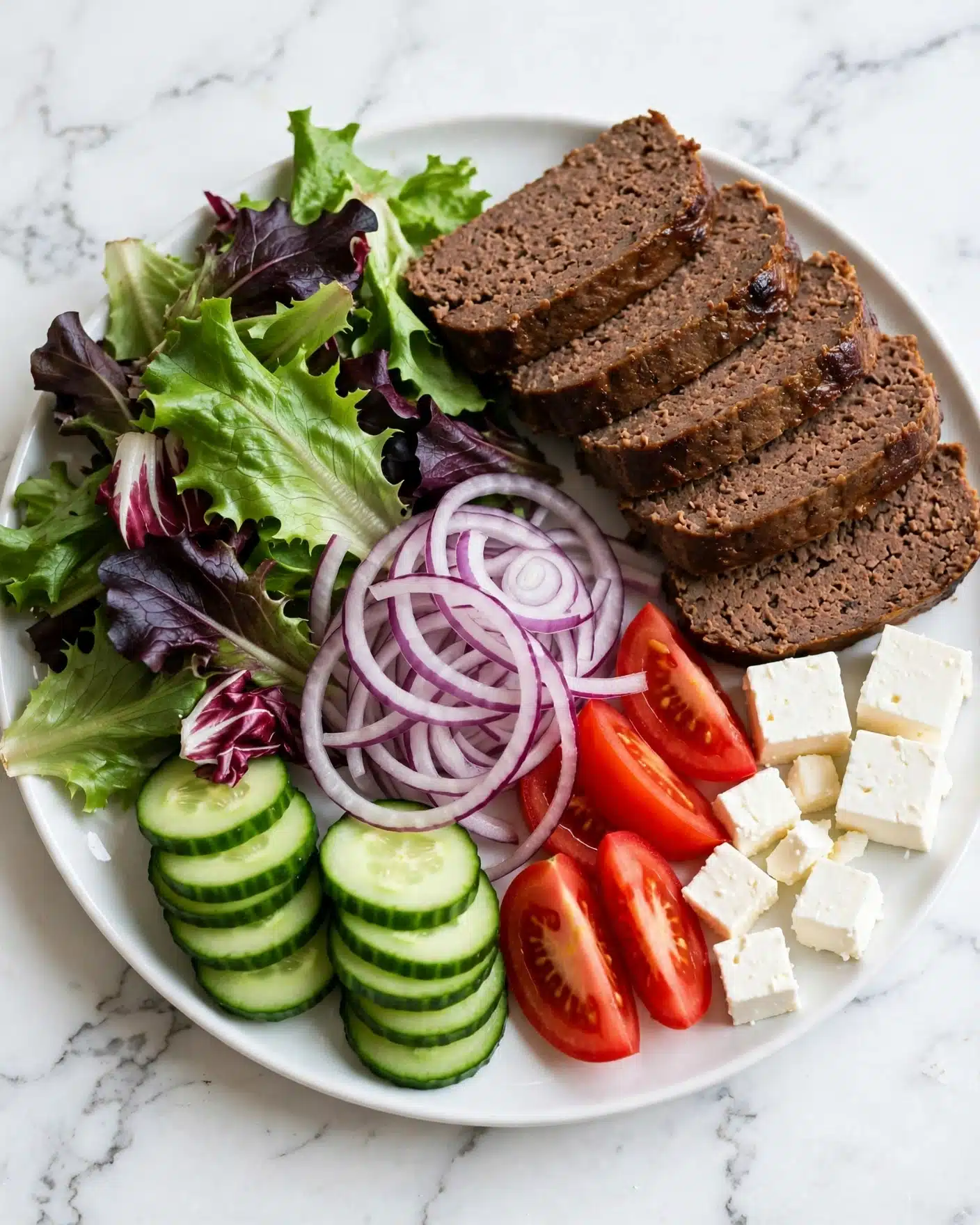 Easy Gyro Meat Recipe 5 A white plate with six slices of brown meatloaf arranged in a fan shape on the right side, showing a slightly textured surface. To the left of the meatloaf, there are four different layers starting from the bottom: thin green cucumber slices, light purple thin onion rings, bright red tomato wedges, and a mix of green and dark red leafy lettuce on the top left corner. The plate sits on a white marbled surface. photo taken with an iphone --ar 4:5 --v 7