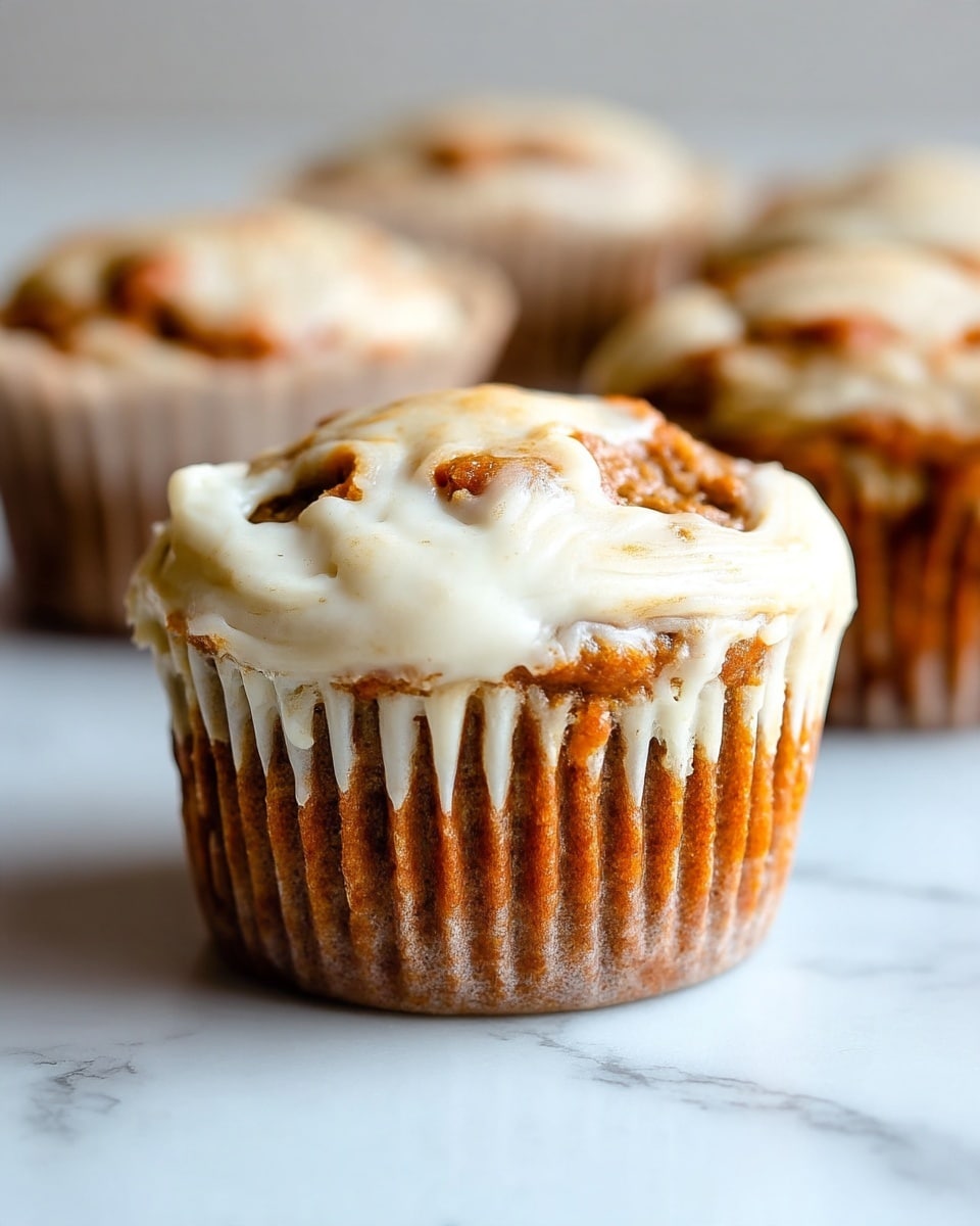 A close-up view of a muffin with two visible layers: the top layer is light beige with a soft, slightly rough texture, and the bottom layer is a rich dark brown with a dense and moist look, both swirling together in a marbled pattern. The muffin is placed inside a white paper liner with ridged edges, sitting on a white marbled surface. In the background, there are parts of other similar muffins slightly out of focus, maintaining the same color and texture details. The lighting is soft, highlighting the contrast between the light and dark parts of the muffin. photo taken with an iphone --ar 4:5 --v 7